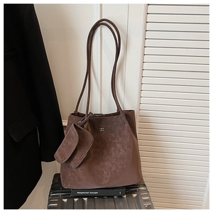 Dettaglio della borsa tote in pelle scamosciata marrone su una valigia metallica