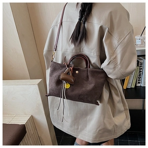 Vue détaillée du sac cabas en daim marron avec breloques sur fond de style de vie chic