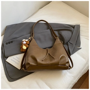 Detail of vintage brown tote bag with leather texture and cute plush bear charm