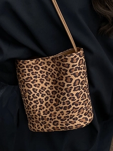 Fashionable leopard print bucket bag with adjustable strap worn by model in dark blazer