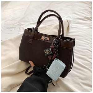Detail of a dark brown PU handbag featuring a metal lock closure and unique charm pendants