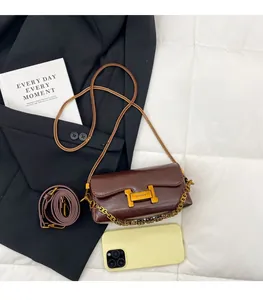 Détail d'un petit sac bandoulière marron avec boucle en H dorée et double bandoulière