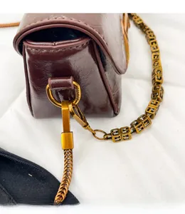 Vue détaillée de la chaîne dorée vintage et de l'anneau en D sur un sac en cuir marron