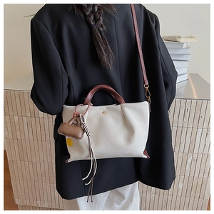 Détail d'un sac à main blanc crème texturé avec anses motif serpent marron et breloque jaune