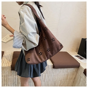Detail of brown faux suede tote bag featuring laser-cut floral patterns and large capacity