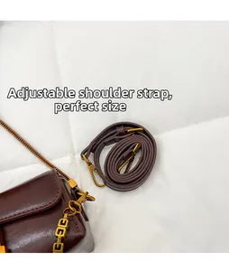 Détail de la bandoulière réglable en cuir et de la chaîne dorée sur le sac marron foncé