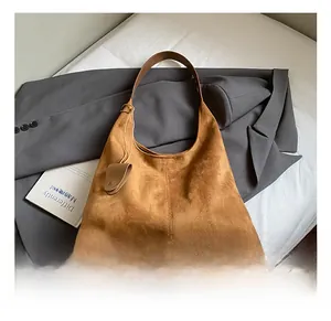 Détail d'un sac cabas en daim marron avec coutures verticales et bandoulière en cuir