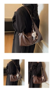 Detail of soft brown leather tote bag with metallic buckle and plush doll charm
