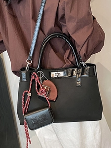 Chic black commuter handbag with contrasting woven charm and silver swivel metal lock