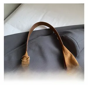 Gros plan sur la couture de la poignée en cuir et texture daim du grand sac cabas