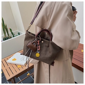 Vue détaillée du sac seau en daim marron avec anses en cuir et pendentif en cœur