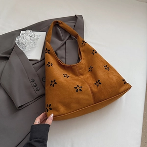 Detail of brown suede tote bag with floral laser cutouts and wide shoulder strap