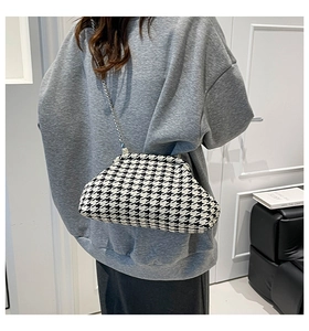 Model showing a chic black and white houndstooth cloud bag with silver chain strap