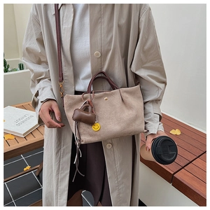 Sac seau en daim beige avec poignées marron et pendentif smiley jaune en détail