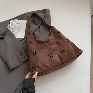 Detail of brown suede hobo bag featuring hollow flower patterns and soft matte texture