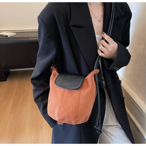 Détail du sac bandoulière bicolore en daim orange avec rabat noir en cuir grainé
