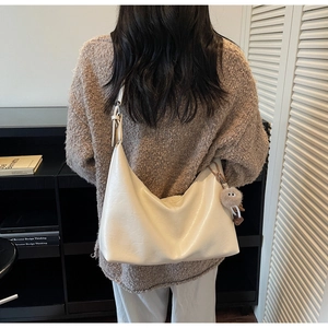 Detailed view of cream soft leather tote bag with brown plush pendant on shoulder