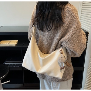 Detailed back view of a large cream soft leather tote bag with a cute plush pendant