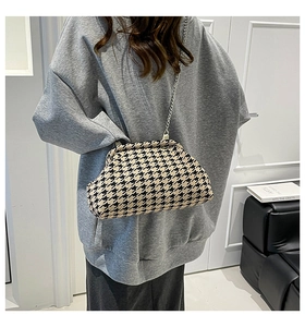 Detail of classic houndstooth fabric texture and silver chain strap on fashion handbag