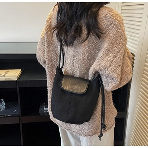 Détail du sac seau noir avec cordon de serrage et empiècement en cuir contrasté