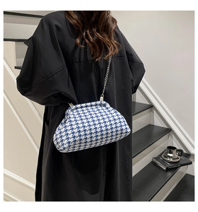 Detail of blue houndstooth cloud bag with silver metal clasp and chain strap