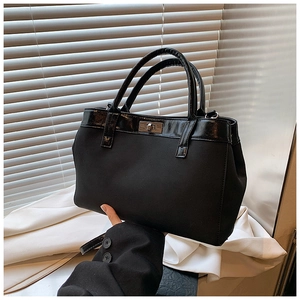 Minimalist black matte crossbody bag with silver twist lock and dual top handles
