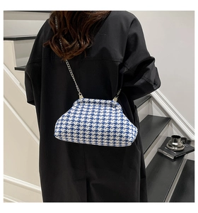 Blue and white houndstooth cloud bag with silver chain strap worn by a model