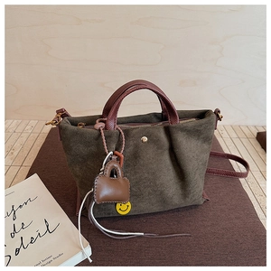 Détail d'un sac cabas en toile vert olive avec poignées en cuir marron et breloques décontractées