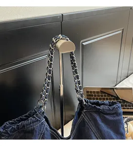 Close-up of woven denim and silver metal chain strap on a large navy tote bag