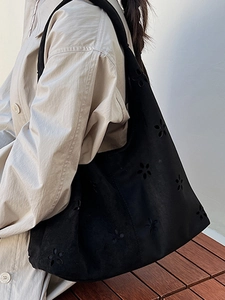 Minimalist black laser-cut hollow tote bag with a soft hobo silhouette on a model