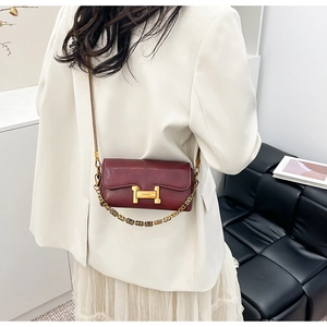 Détail du sac à bandoulière en cuir rouge foncé avec chaîne dorée et boucle métallique en H