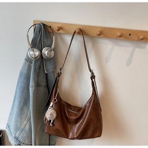 Detail of dark brown vintage hobo bag with a cute plush monster charm on the shoulder strap