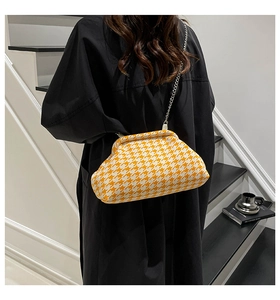 Close-up of yellow houndstooth pattern bag with silver metal chain and vintage clasp