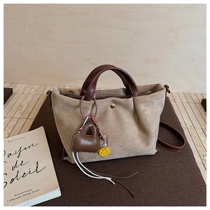 Détail du sac à main en daim beige avec poignées en cuir marron et breloque en forme de cœur