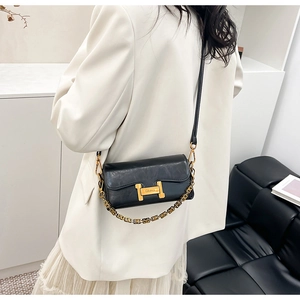 Détail du sac bandoulière en cuir noir avec boucle dorée en H et chaîne métallique
