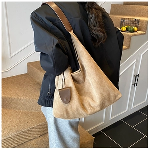Détail du sac hobo en daim kaki avec bandoulière en cuir marron sur un mannequin