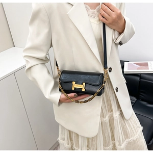 Détail du sac carré en cuir noir avec boucle H dorée et bandoulière chaîne en métal