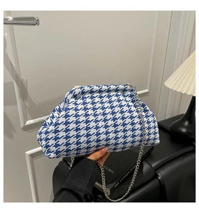 Detail of blue and white houndstooth knit cloud bag with silver chain and metal clasp