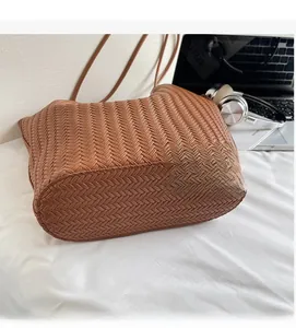 Detail view of the brown woven tote bag featuring a V-shaped texture on a white cloth surface