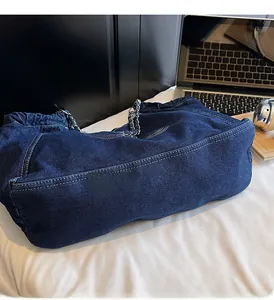 Detailed macro of dark blue denim tote bag with white stitching and metal chain strap