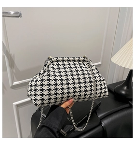 Detail of a houndstooth cloud bag with classic silver chain strap and metal frame closure