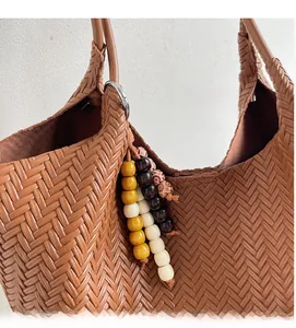 Detail of brown woven tote bag featuring decorative colorful beads and metallic ring