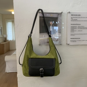 Detail of green suede hobo bag featuring black leather flap pocket and white stitching