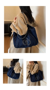 Detail of blue denim tote bag featuring silver chain strap and white logo embroidery