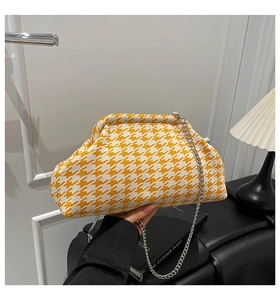 Detail of yellow houndstooth knitted cloud bag with elegant silver metal chain strap