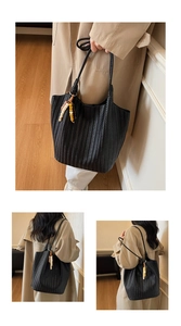 Close-up of black woven tote bag with V-shaped texture and bohemian beaded charm