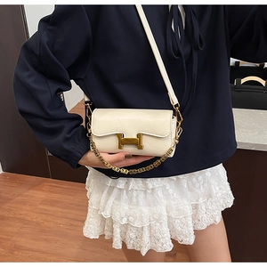Détail du sac bandoulière en cuir crème avec boucle H dorée et chaîne sur le mannequin