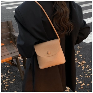 Close-up of a light brown lychee pattern leather tote bag worn by a model in sunlight