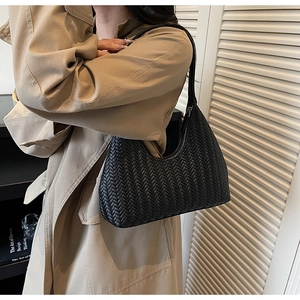 Détail du sac croissant en cuir tressé noir montrant la texture complexe en motif V