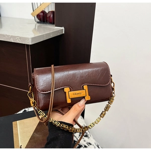Gros plan d'un sac à main en cuir marron avec boucle métallique dorée en forme de H chic